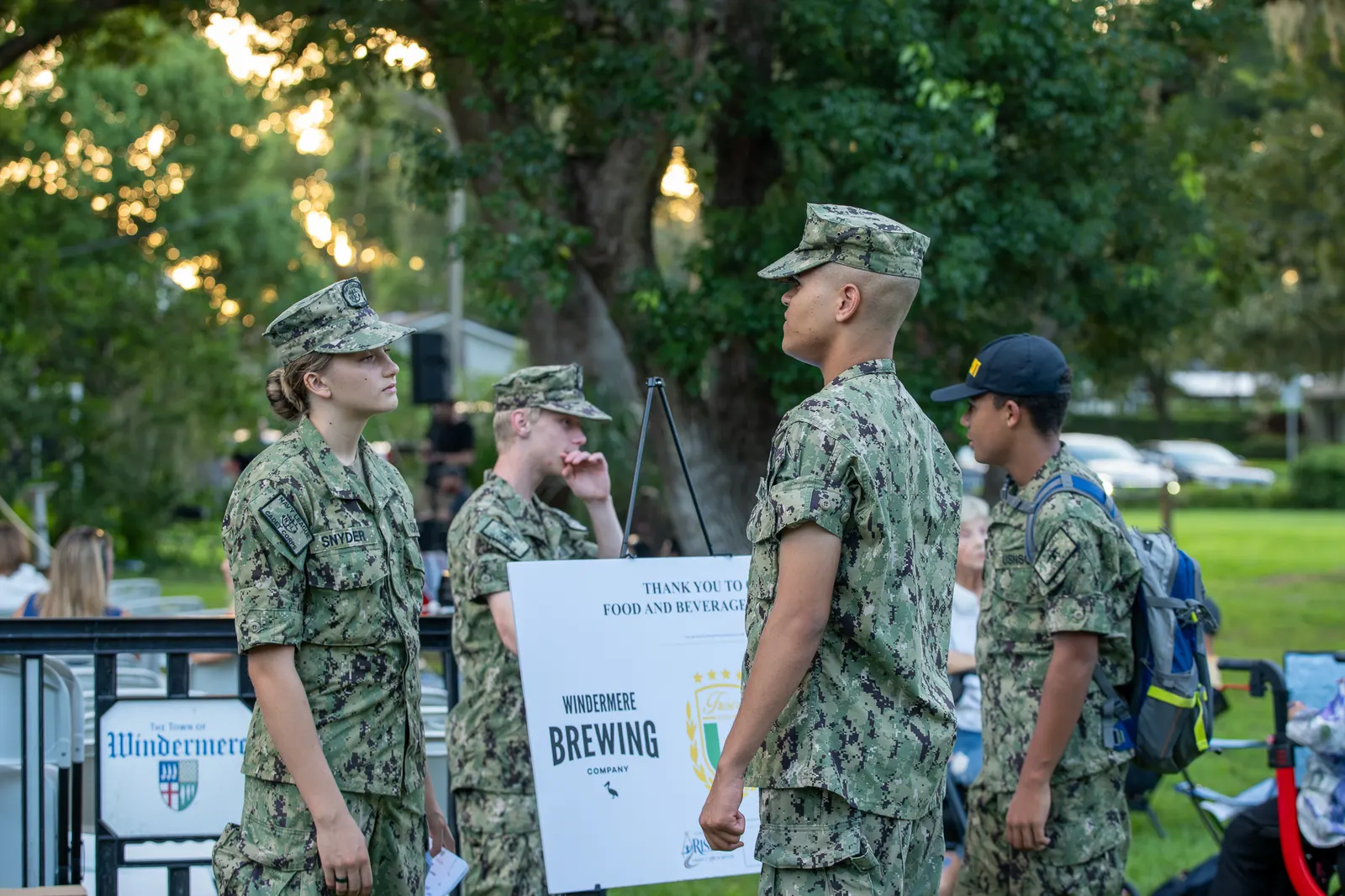 Uniformed Sea Cadets gather beside the event welcome sign.