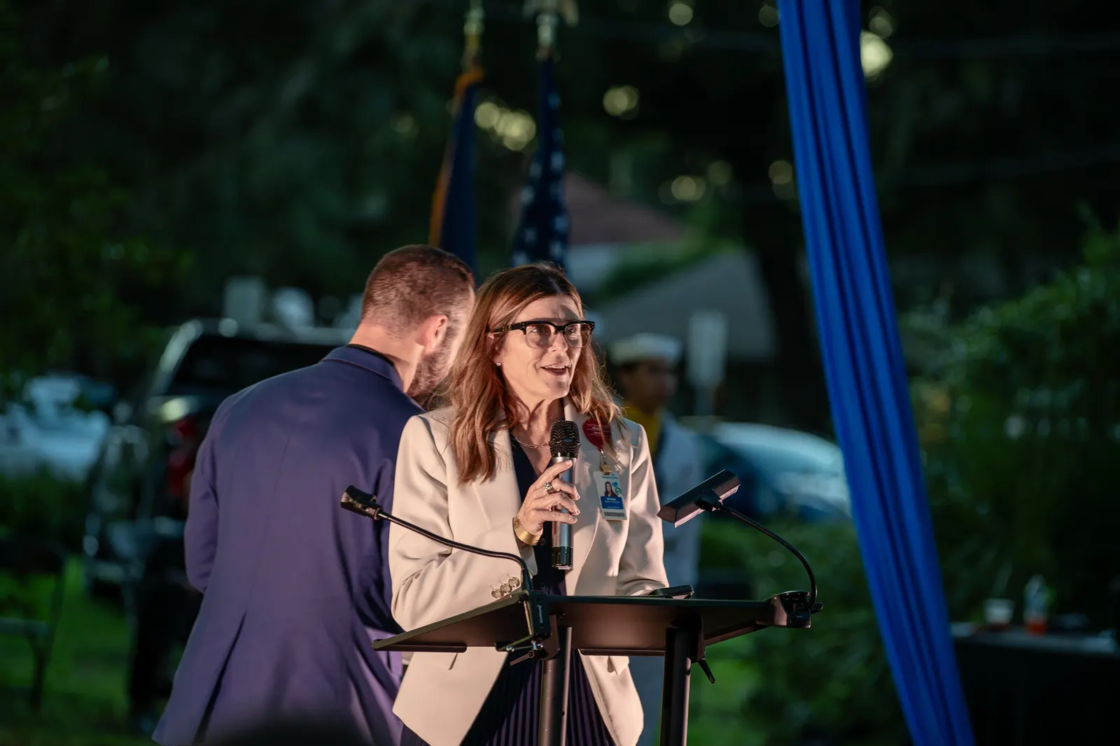 Two presenters embrace beside the lectern during the ceremony.