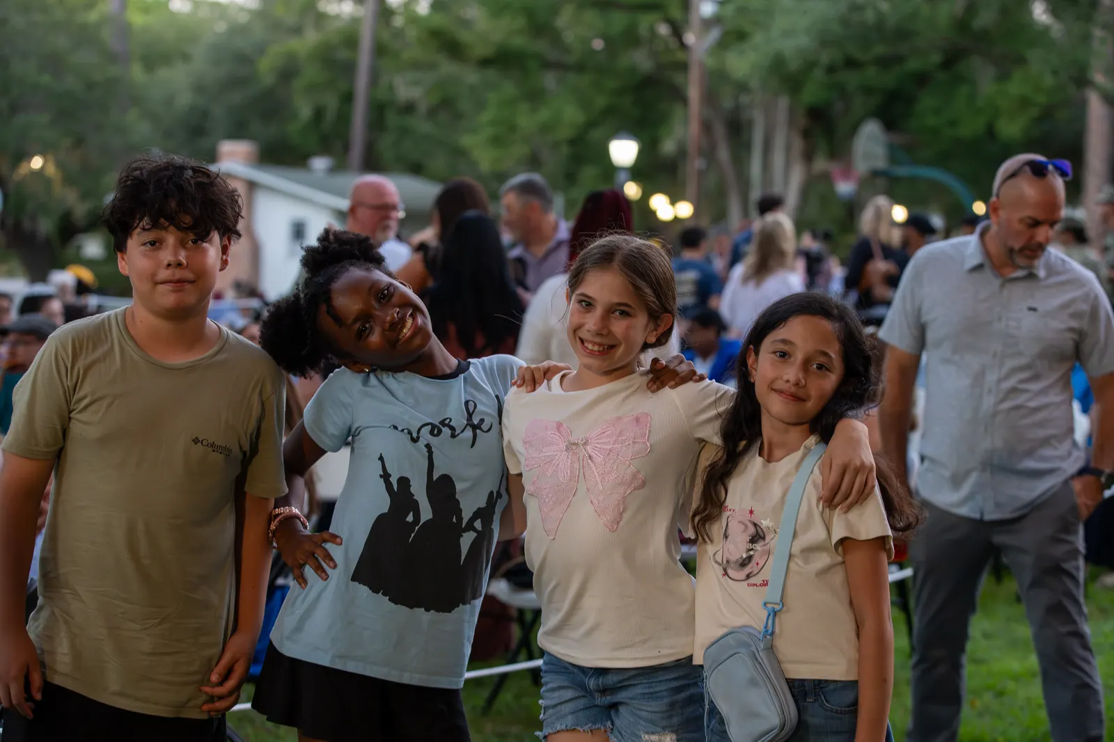 A group of young guests smile with the event crowd behind them.