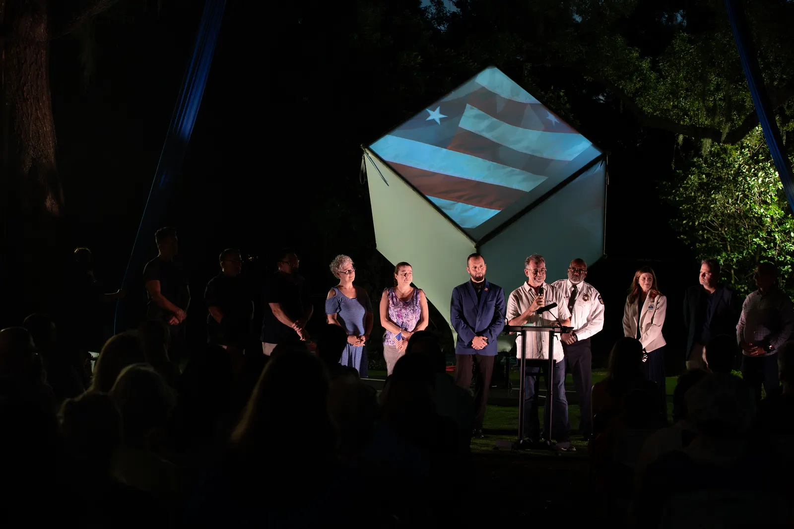 A wide nighttime view shows the full group gathered onstage.