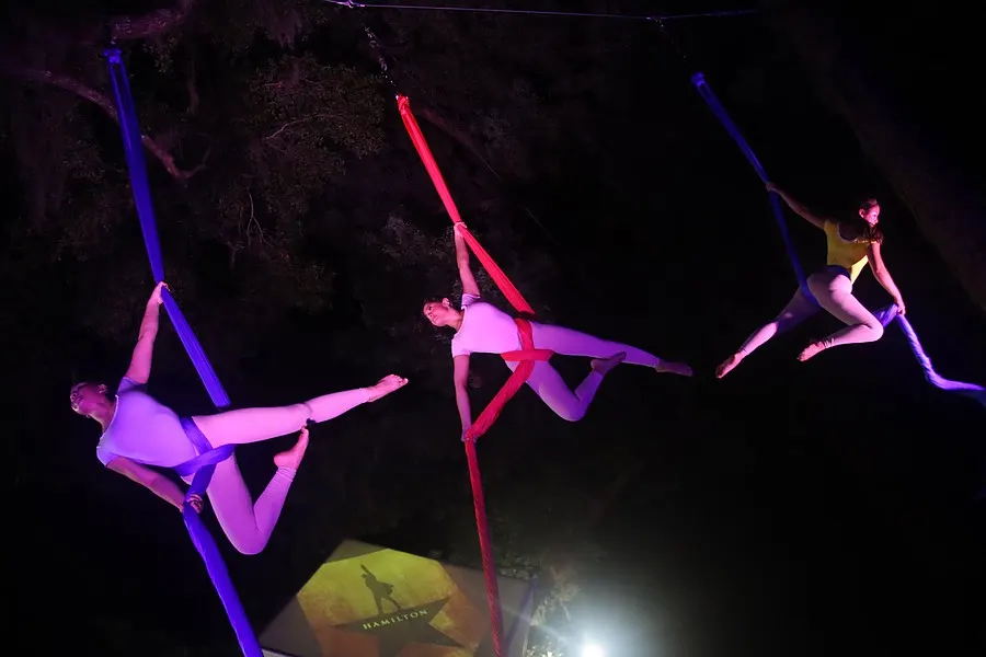 Three aerialists perform simultaneously on suspended silks.