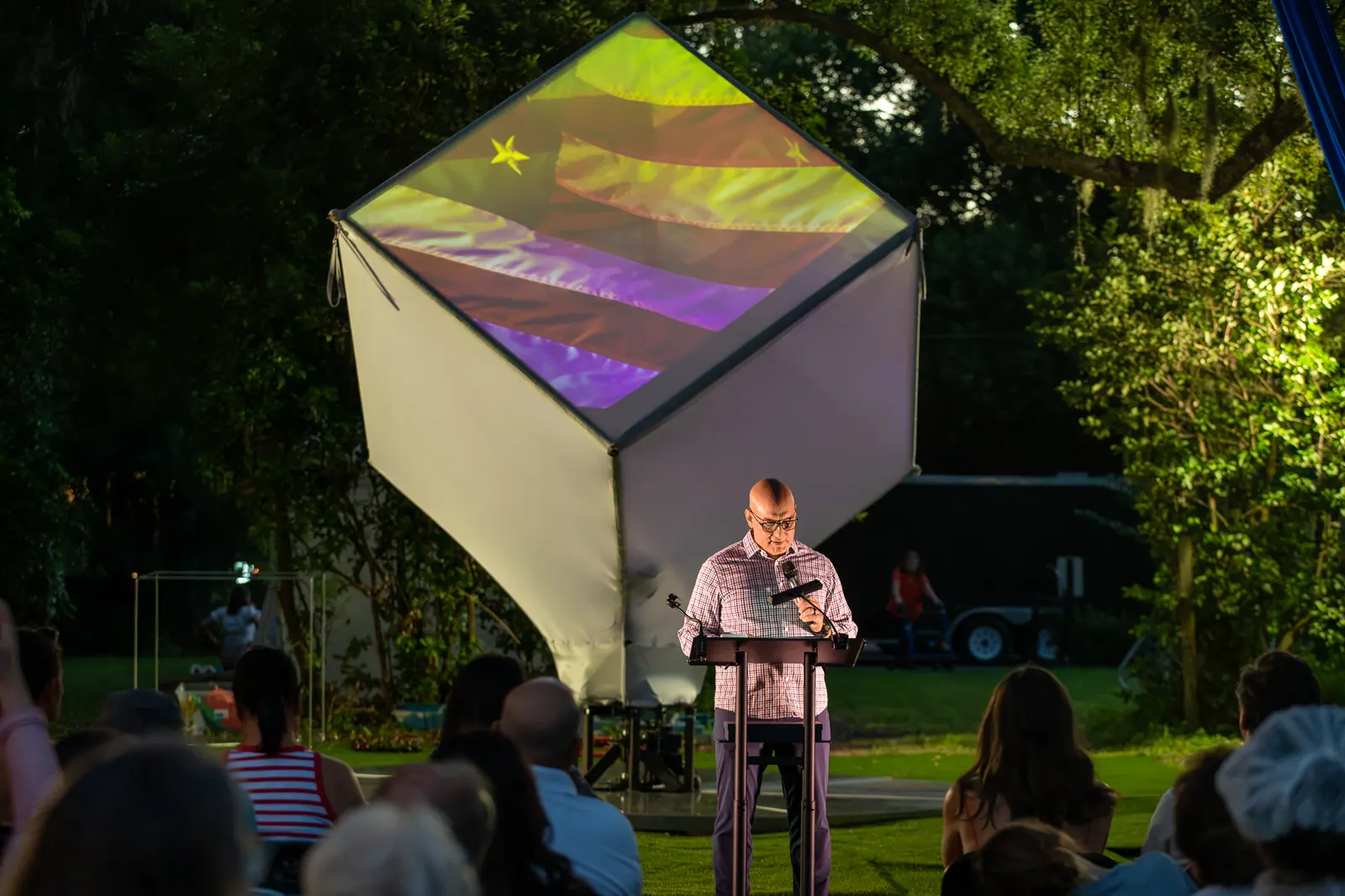 Another speaker addresses the crowd with the cube glowing behind him.