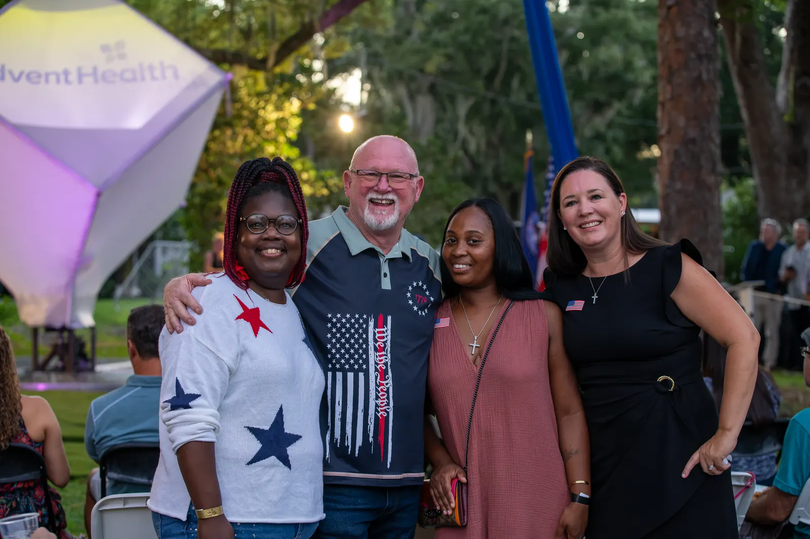 Four guests pose beside the illuminated performance structure.