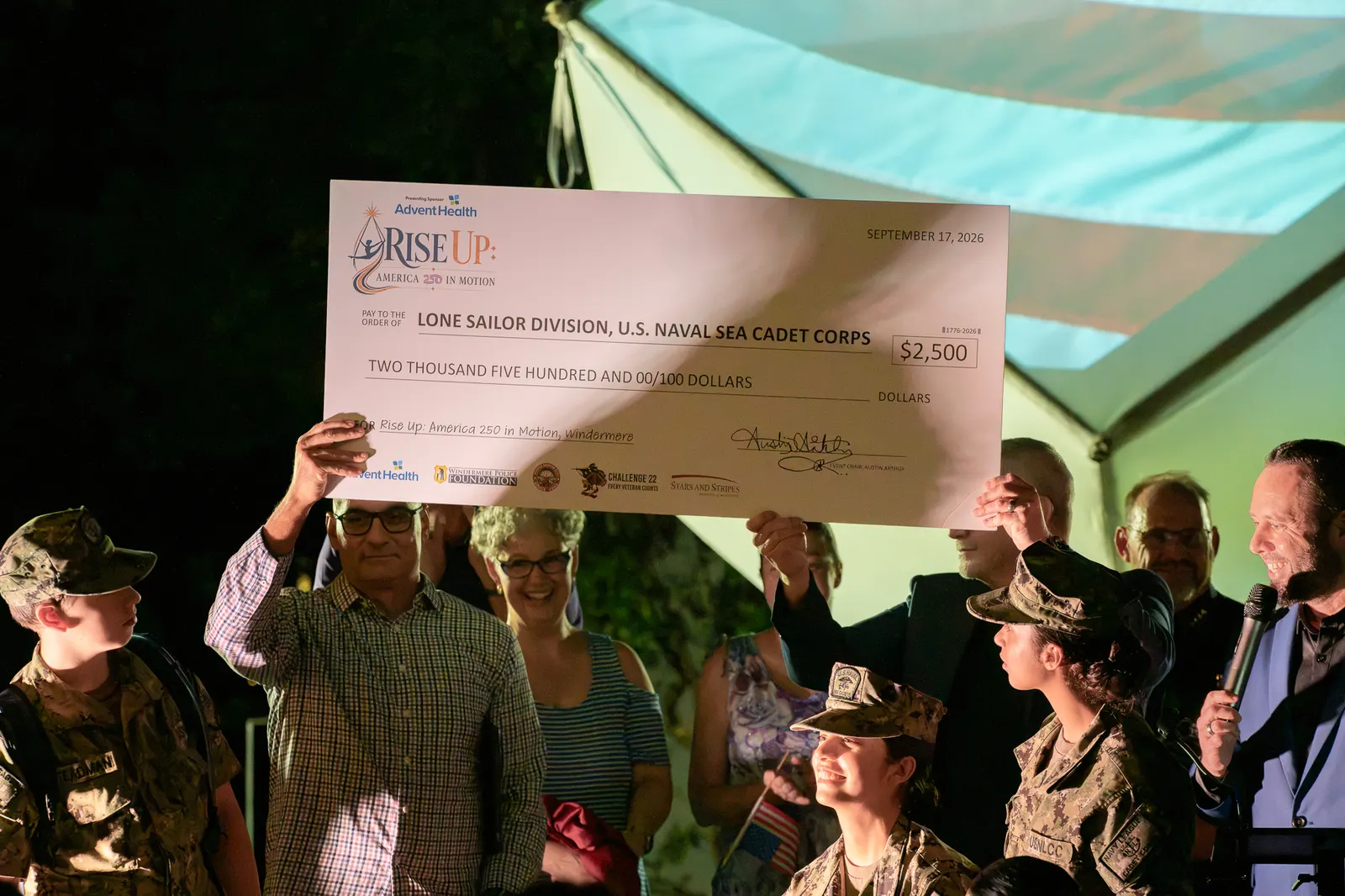 Sea Cadets and community leaders hold a ceremonial donation check.