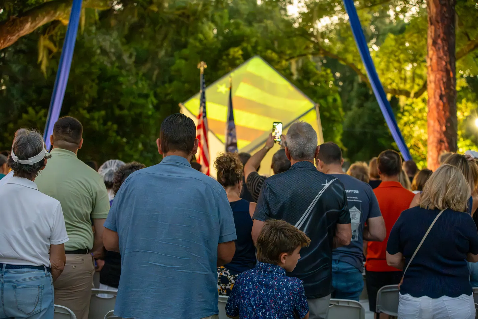 A broad rear view shows standing guests facing the illuminated cube.