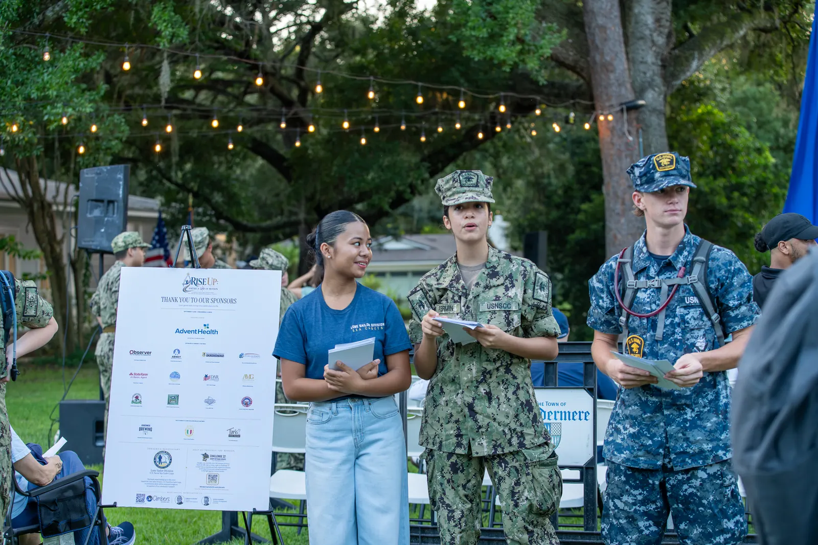 A volunteer speaks with Sea Cadets near the sponsor display.