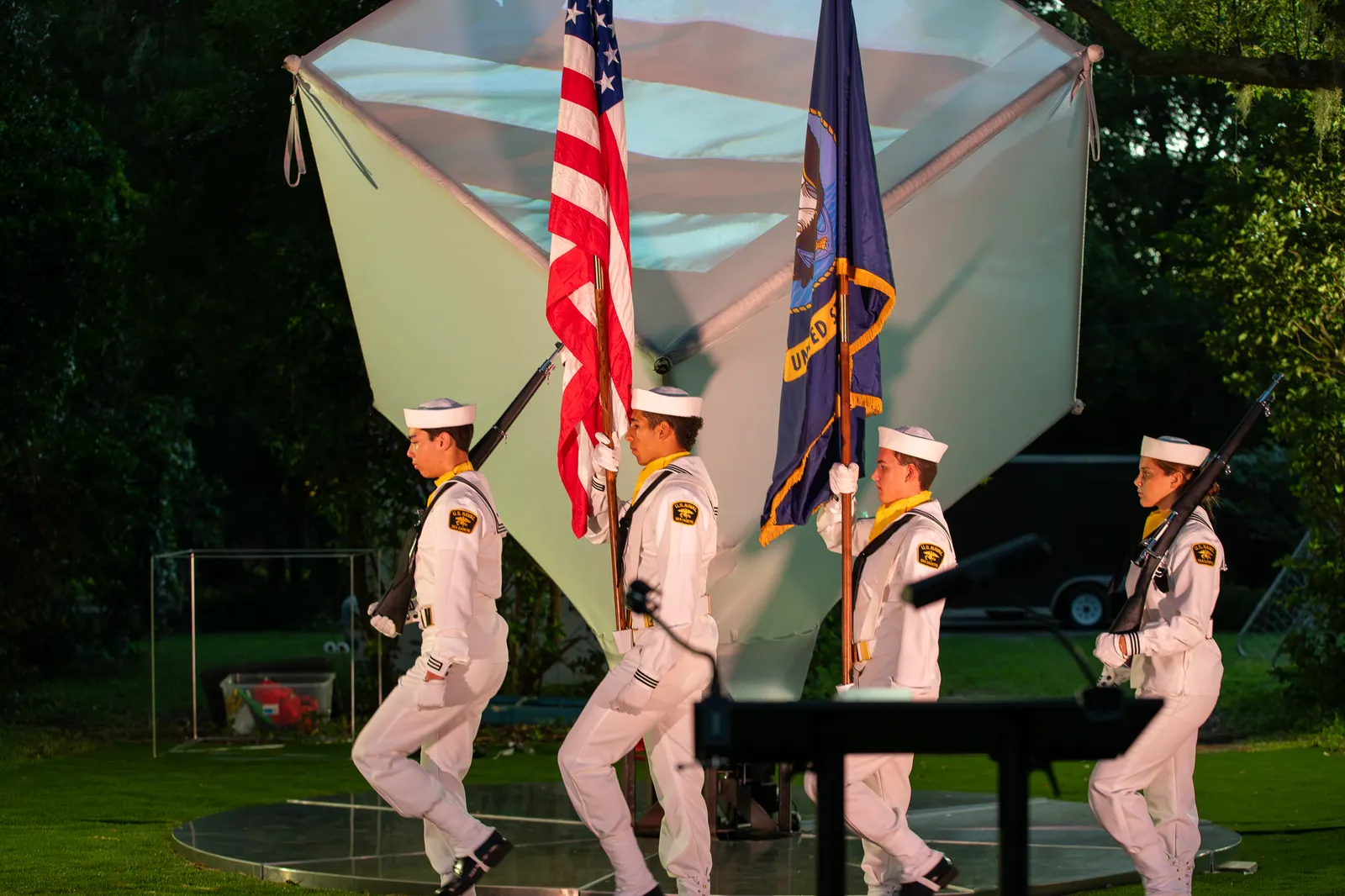 The Sea Cadet color guard advances toward the stage with flags.