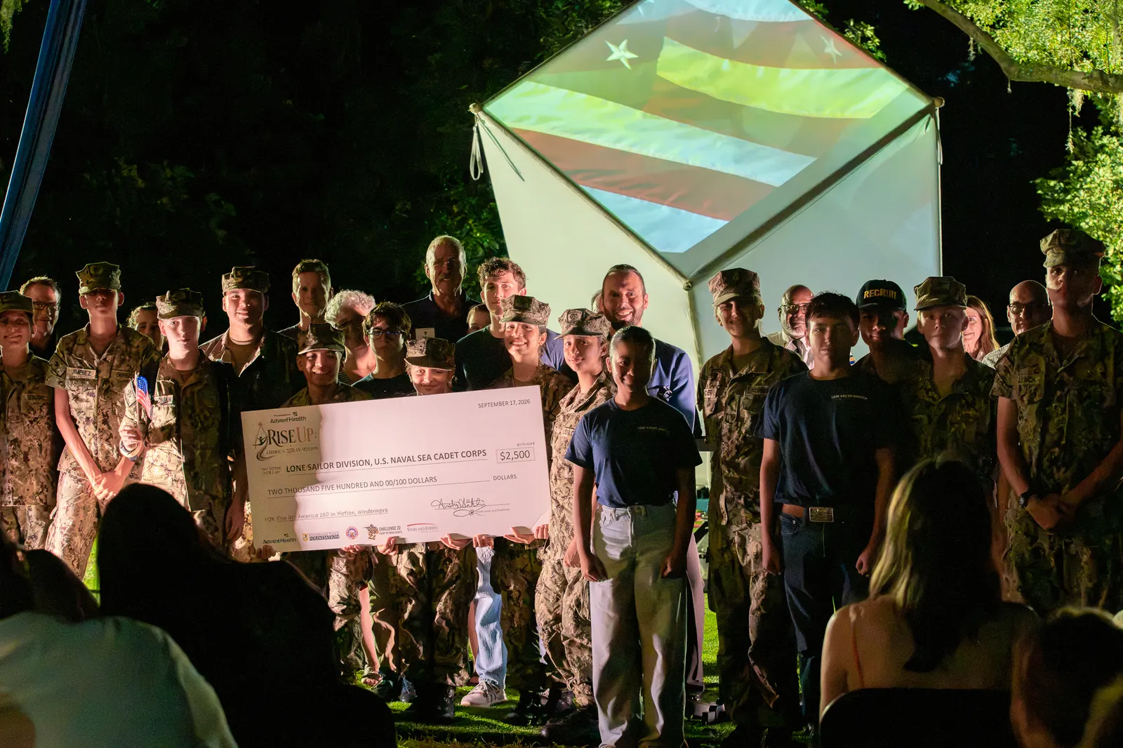 The check presentation group stands beneath the green-lit cube.