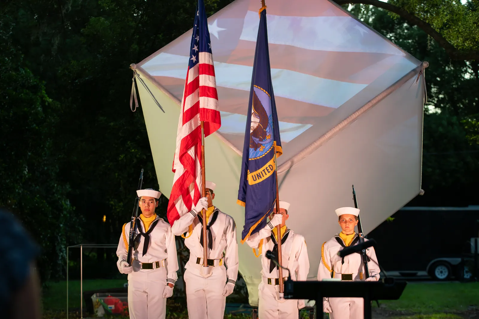 Sea Cadets stand at attention with the American and unit flags.