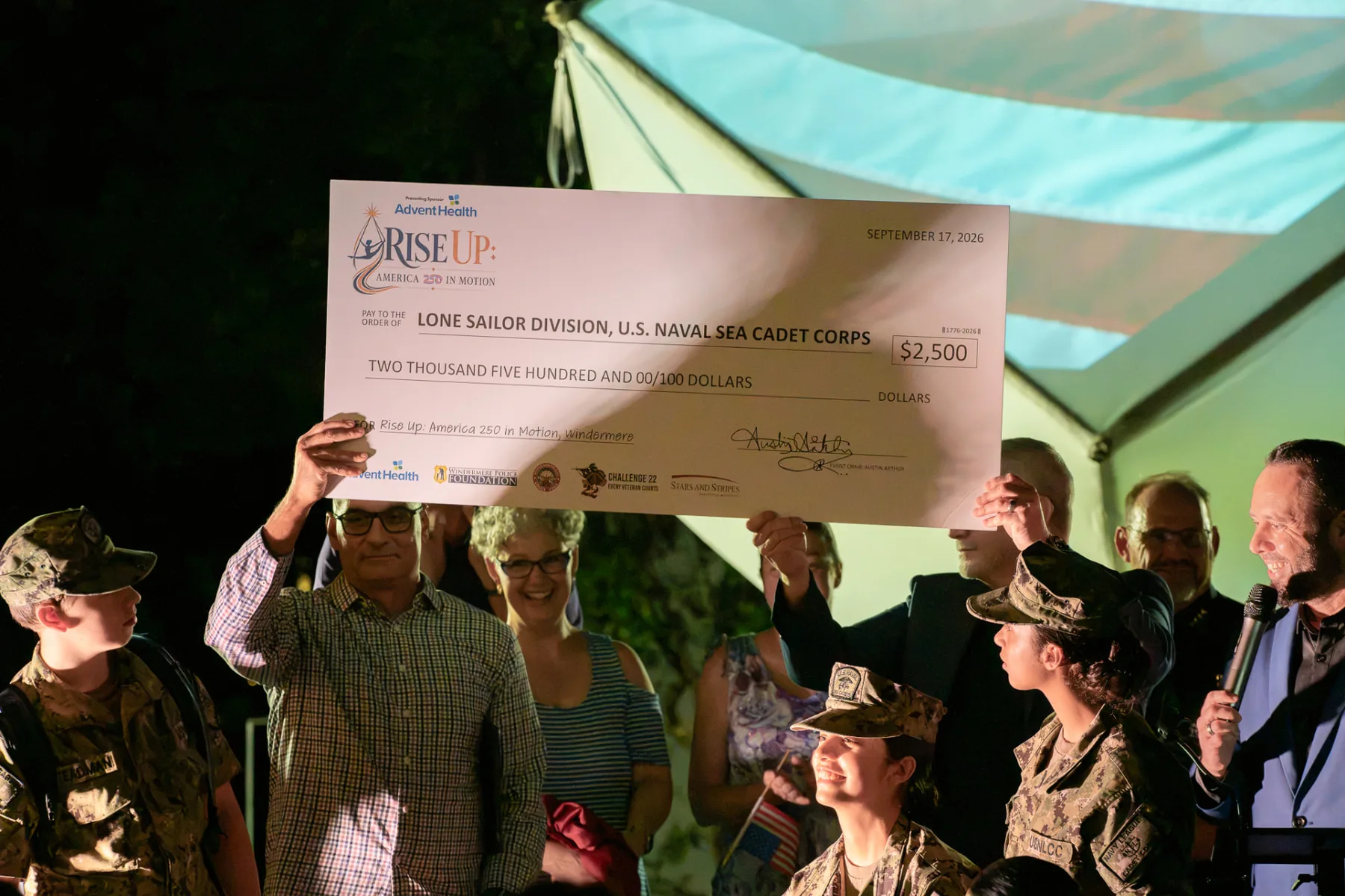Community members hold a ceremonial $2,500 check for the Lone Sailor Division, U.S. Naval Sea Cadet Corps.