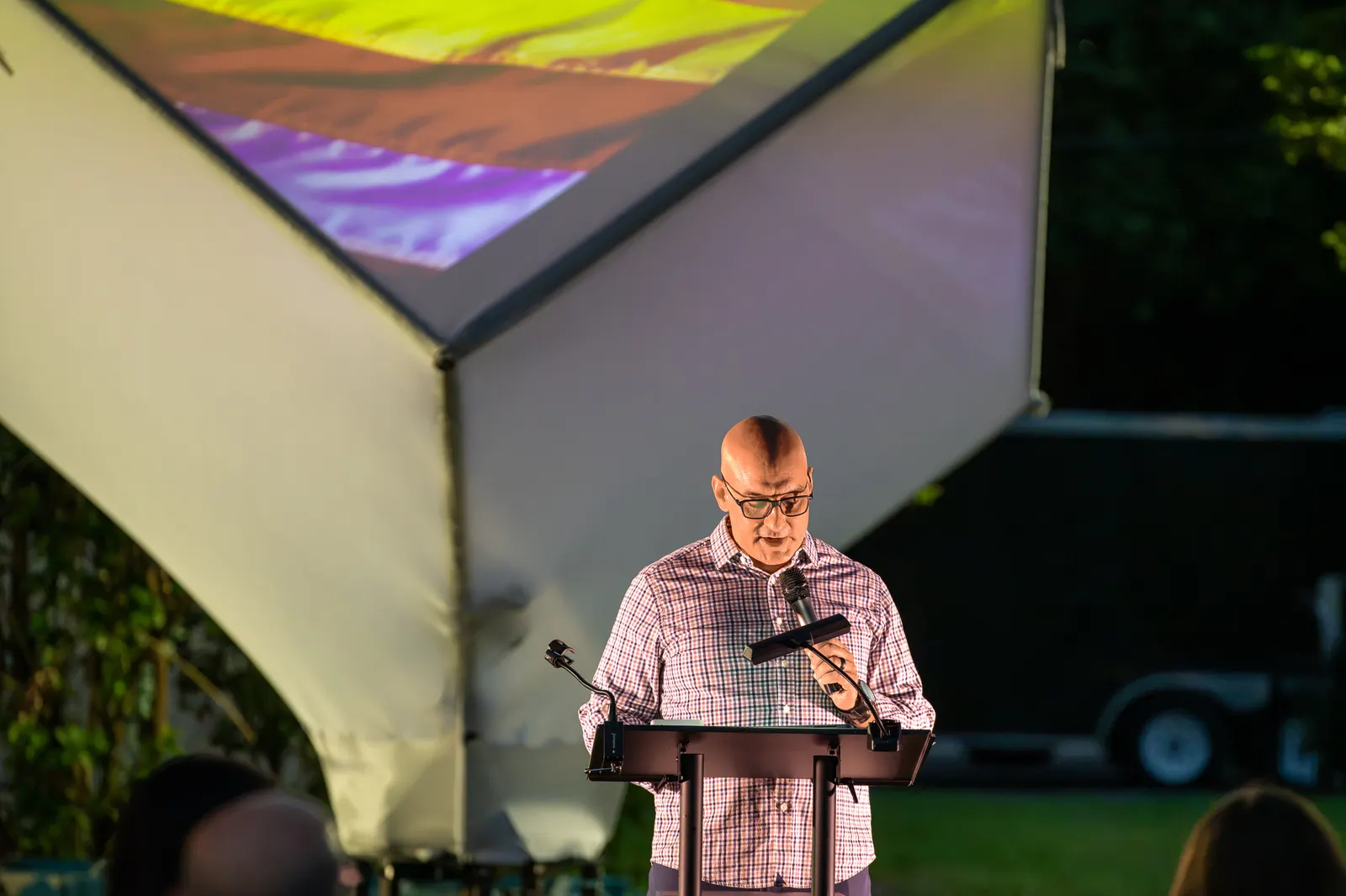 A close view shows a man reading notes at the lectern.