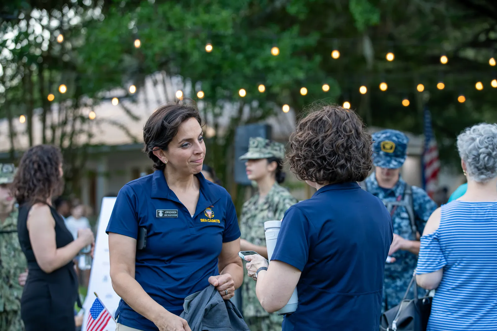 Guests talk beneath string lights before the outdoor program begins.