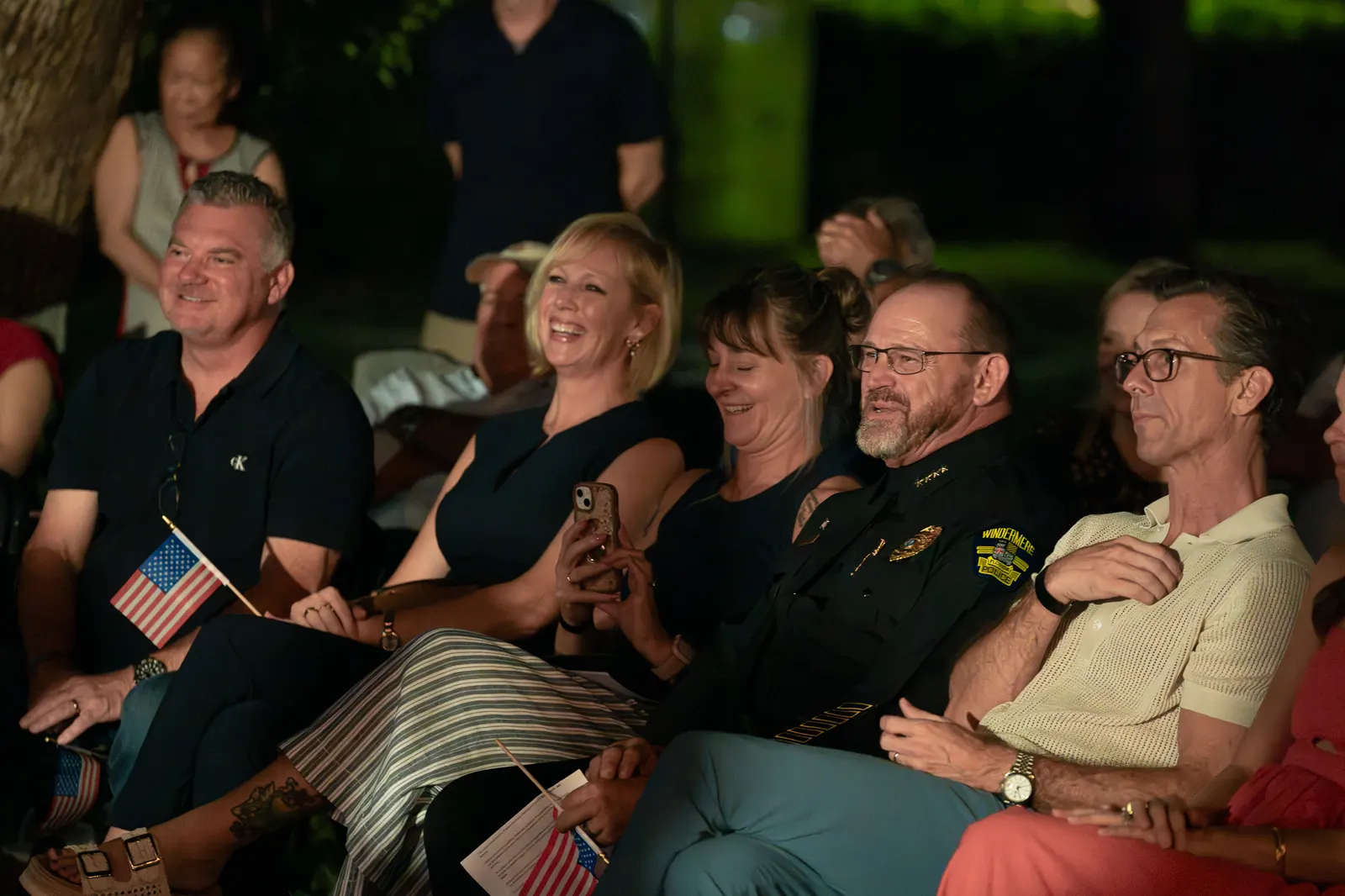 Uniformed guests and community members smile from the front row.