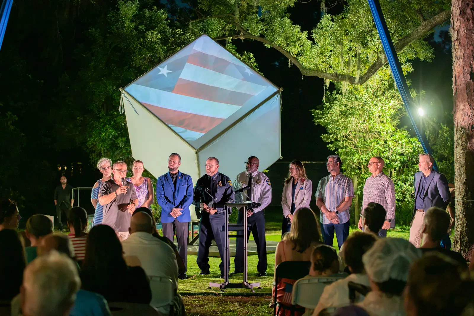 The recognition group stands together with the cube glowing blue behind them.