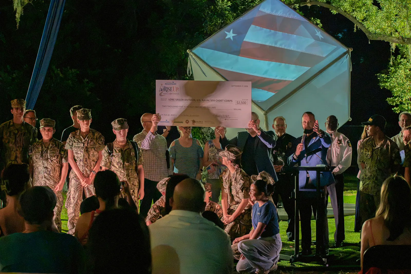 Guests photograph the Sea Cadets and presenters holding the check.