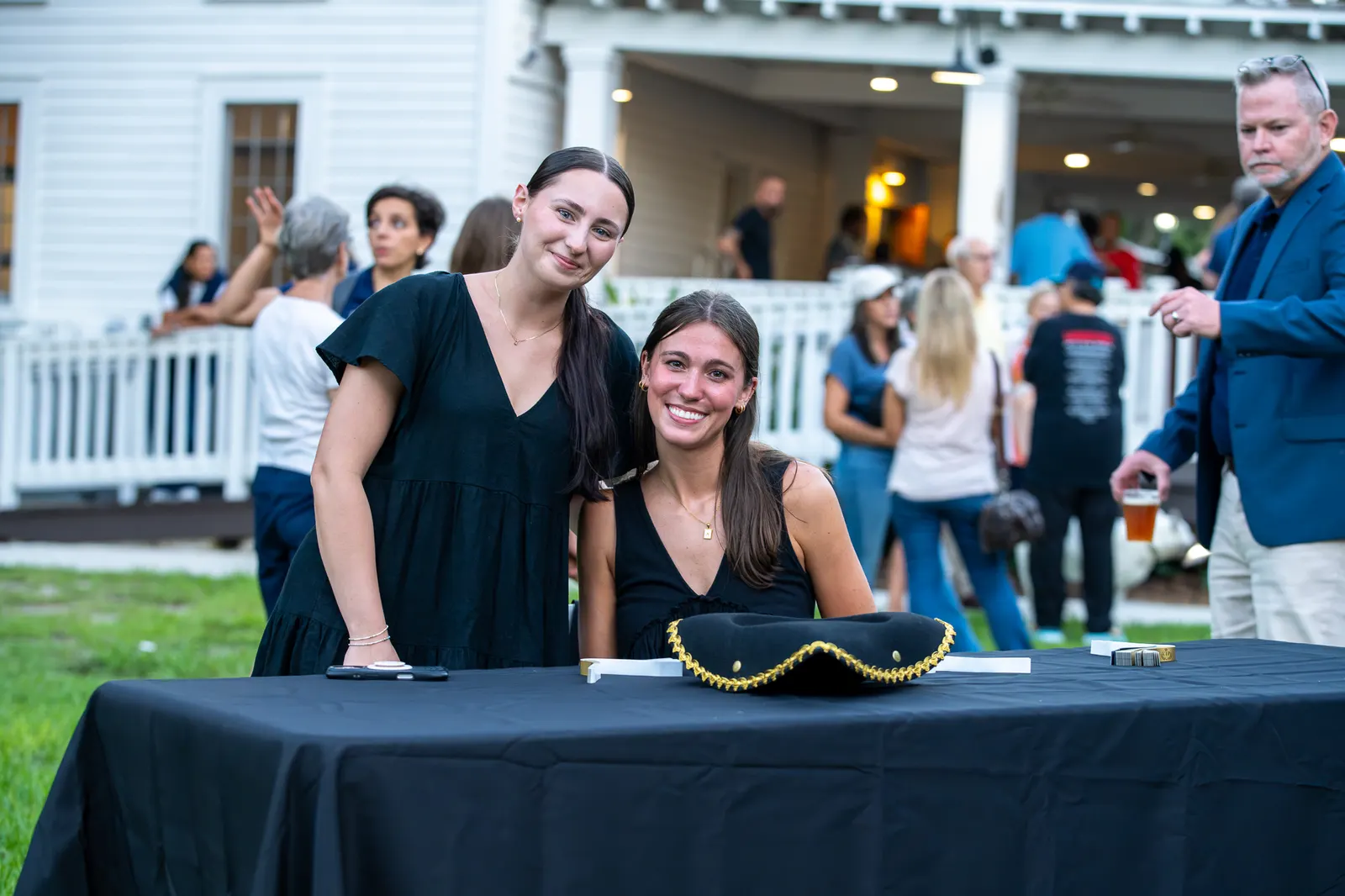 Three women smile together behind a black registration table.