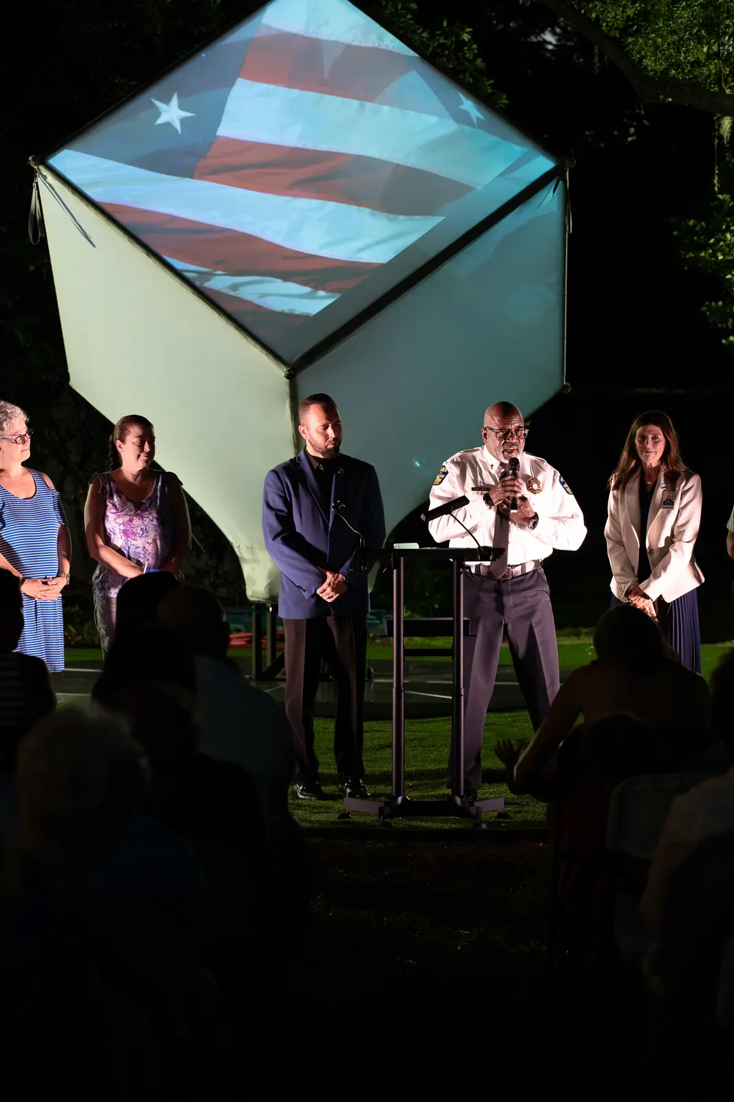 Community partners stand in a line while remarks continue at the lectern.